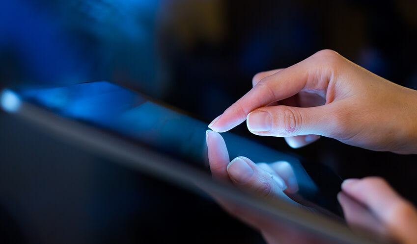 A woman holding a tablet with one hand and touching it with another